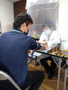 医師の問診を受けるスタッフ